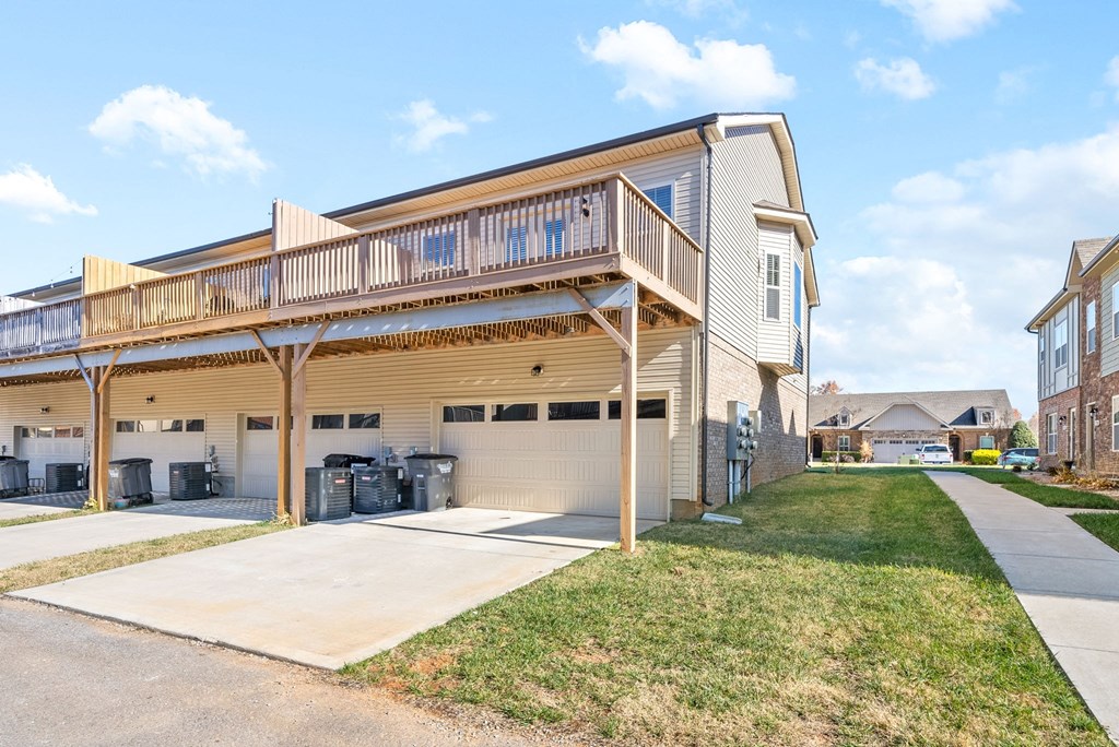 the back of a house with a garage and a porch with a lawn