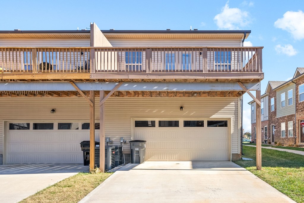 the front of a house with a garage door and a deck