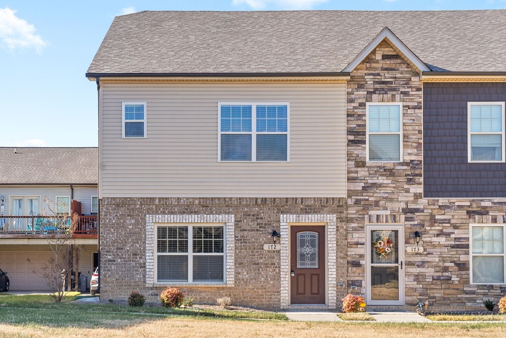 a brick house with a brown door and a tan roof