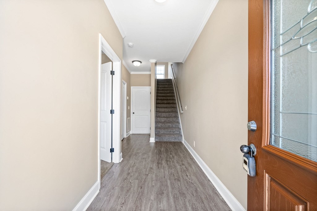 a hallway with a wooden door and a staircase in a house