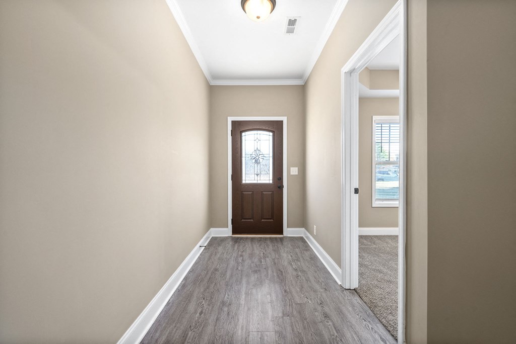 an empty living room with a door to a hallway with white walls and wood floors