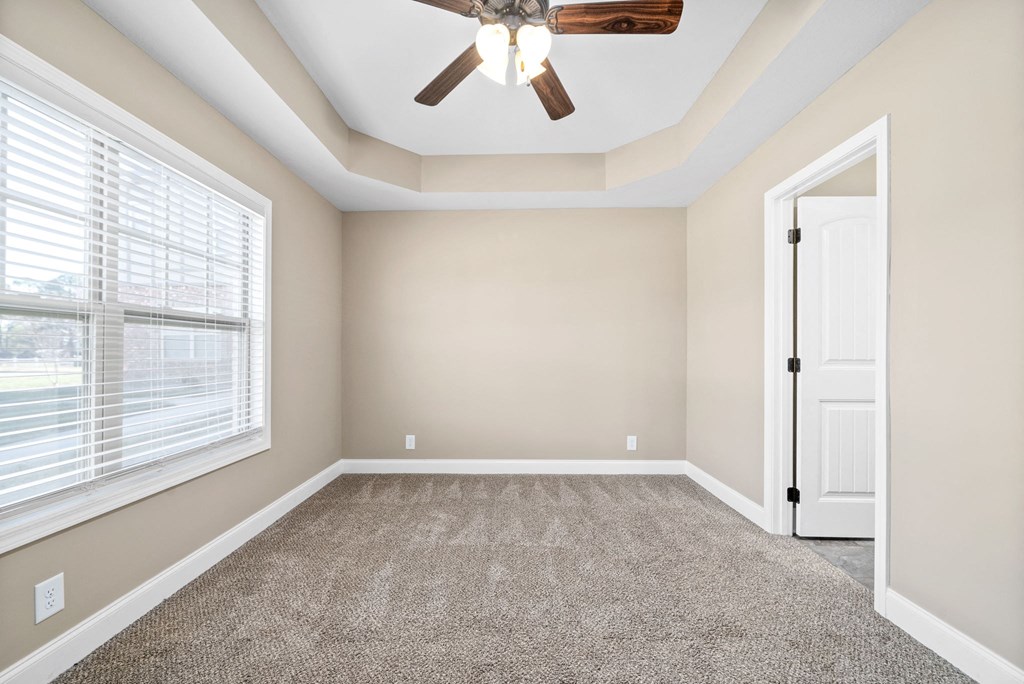 an empty living room with a ceiling fan and a window