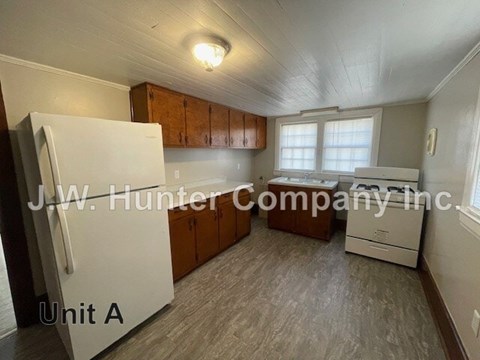 A kitchen with a white fridge and wooden cabinets.