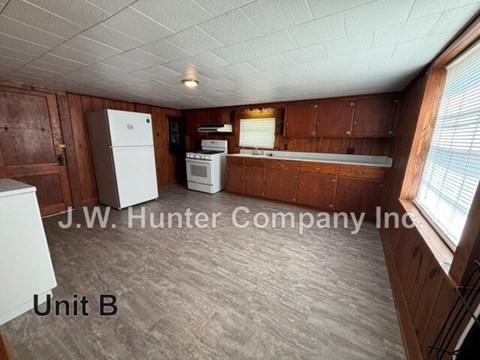 A kitchen area with wooden cabinets and a white refrigerator.