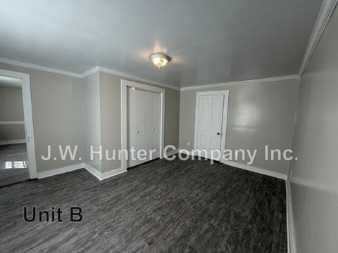 A room with a wooden floor and white walls, with a light fixture on the ceiling.