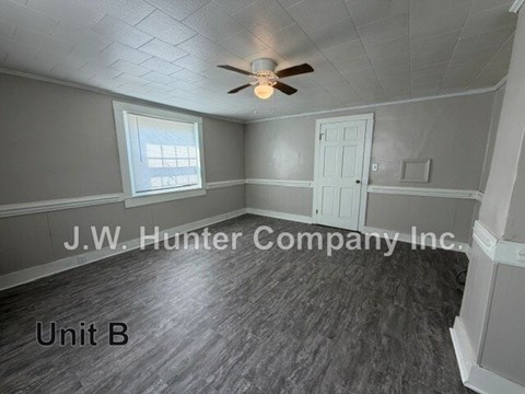A room with a ceiling fan and a window with blinds.
