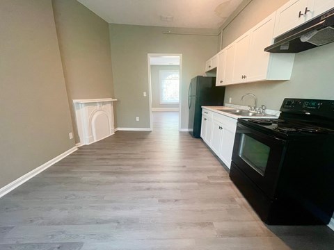 A kitchen with black appliances and white cabinets.