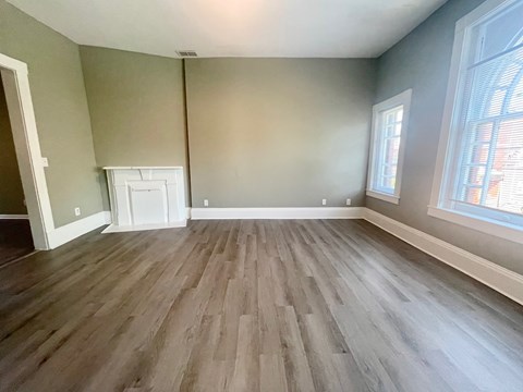 A room with wooden flooring and a window on the right side.