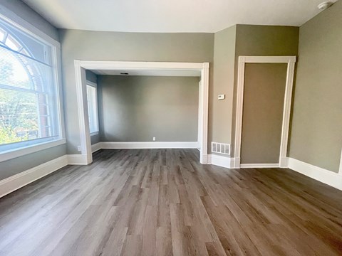A room with wood flooring and a large window.