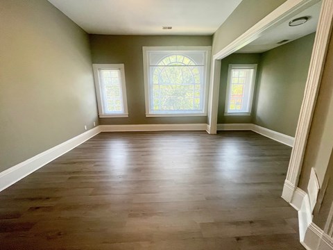 A room with wooden floors and a large arched window.