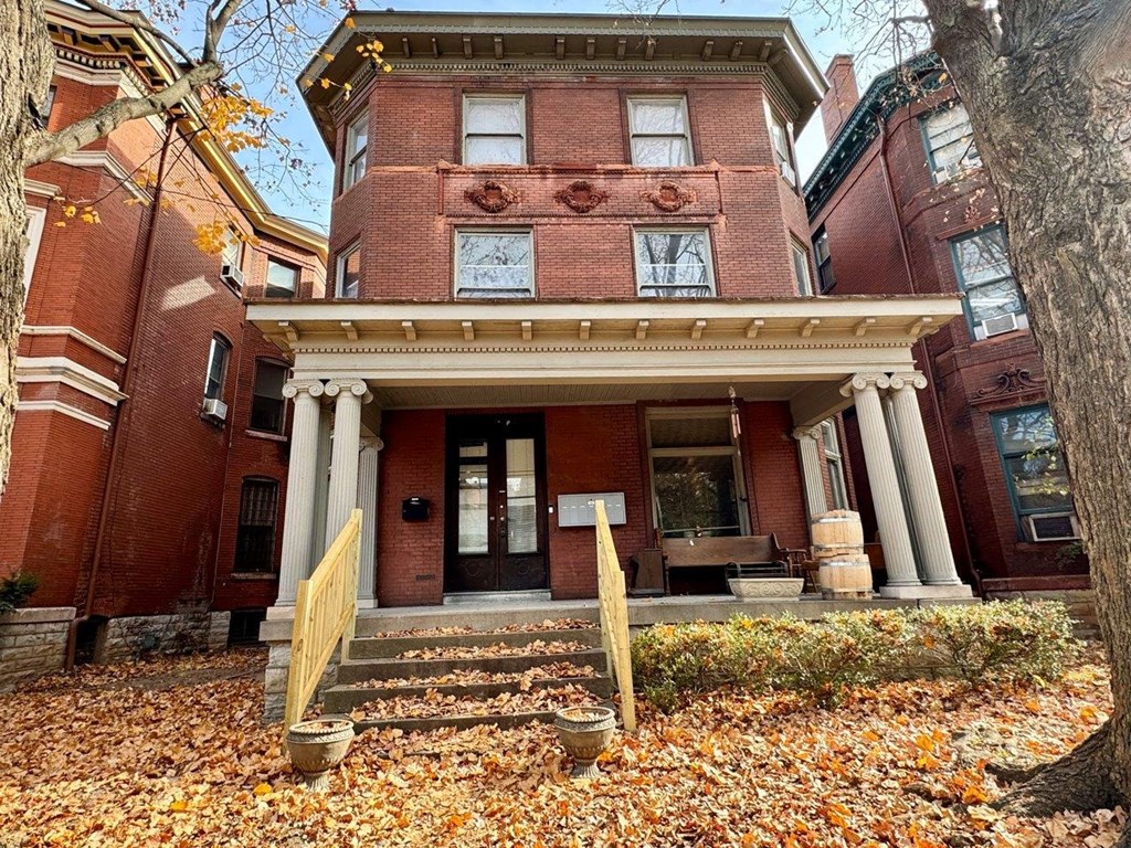 the front of a red brick building with some leaves on the ground