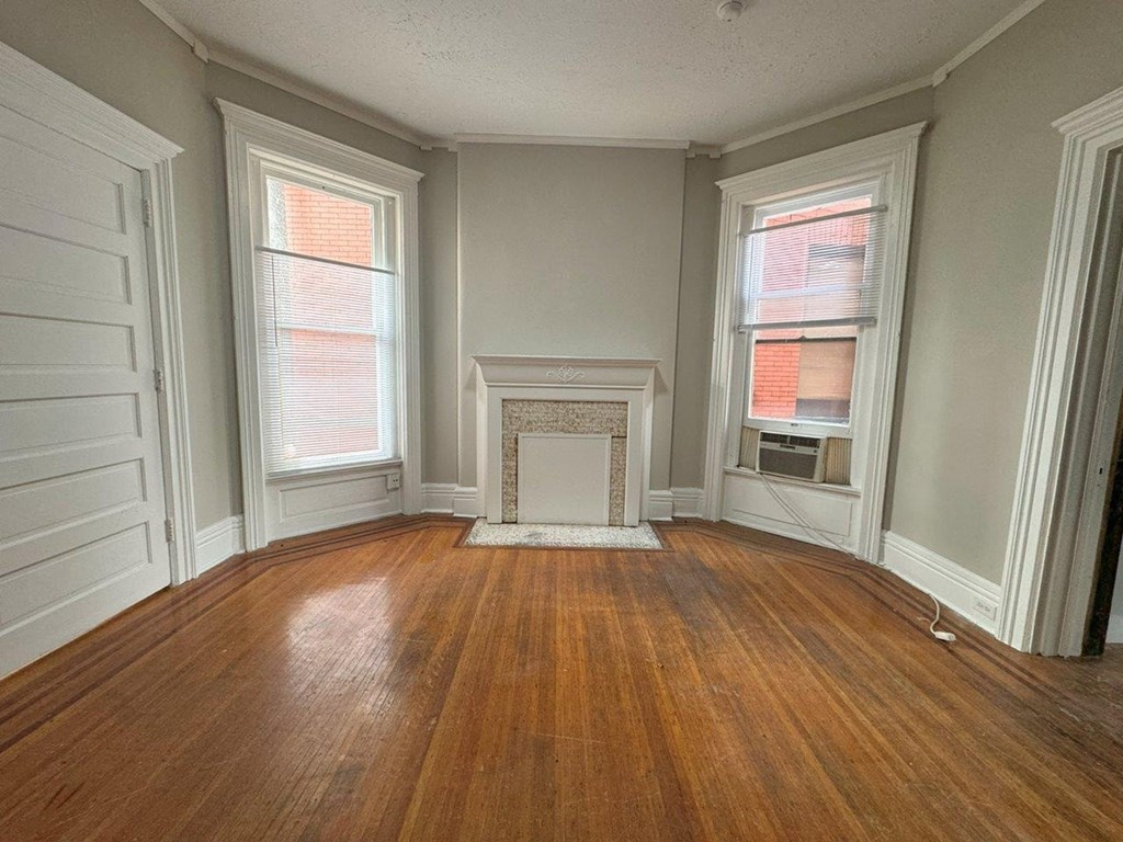 an empty living room with wood floors and a fireplace