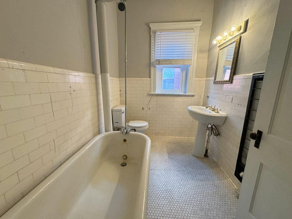 a bathroom with a tub and a sink and a window