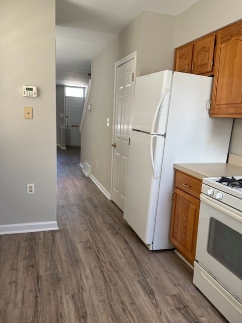 A kitchen with a white refrigerator and wooden cabinets.