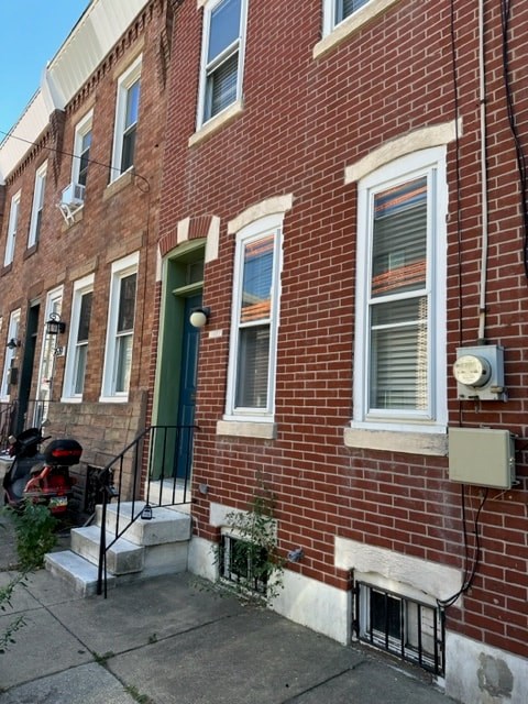 A red brick building with a green door and a mailbox on the right side.