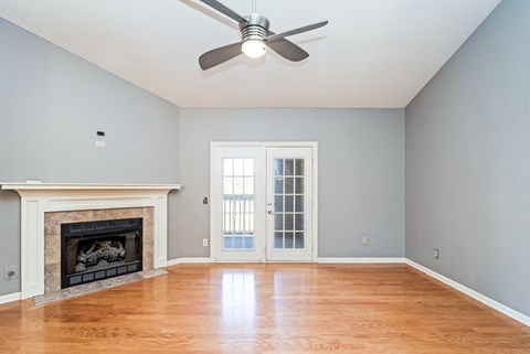 an empty living room with a fireplace and a ceiling fan