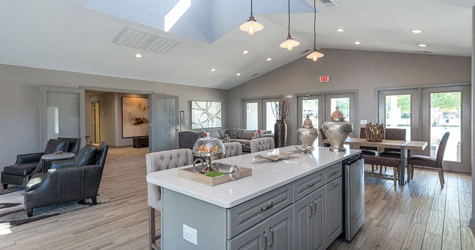 clubroom with vaulted ceilings, pendant lighting and a large island with seating