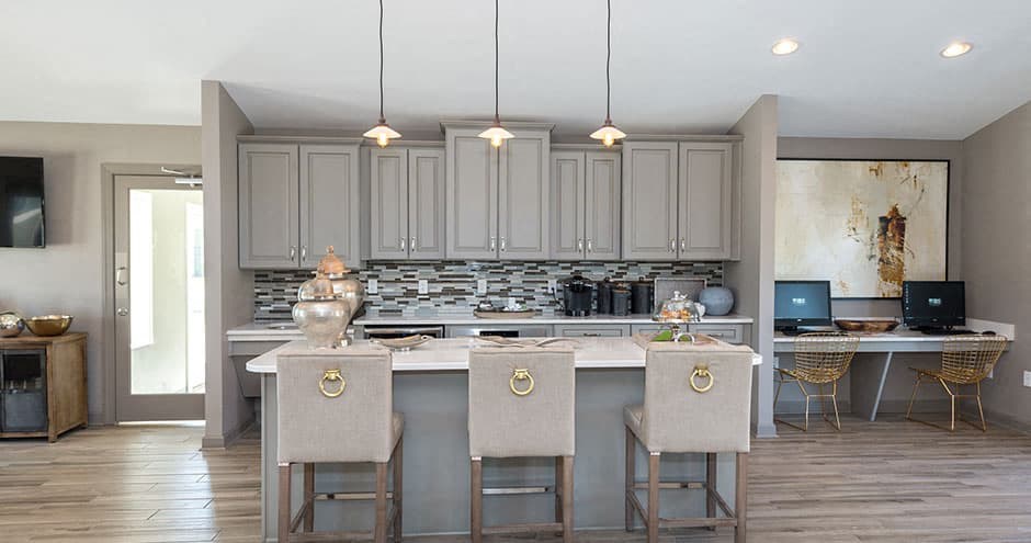 gray cabinets with large island, pendant lighting and white bar stools