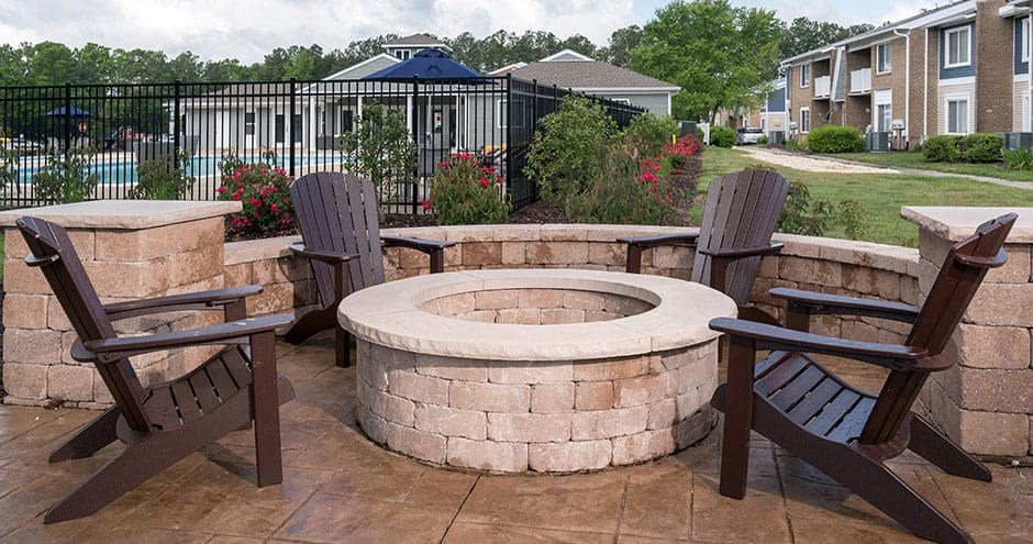 outdoor stone firepit with brown adirondack chairs