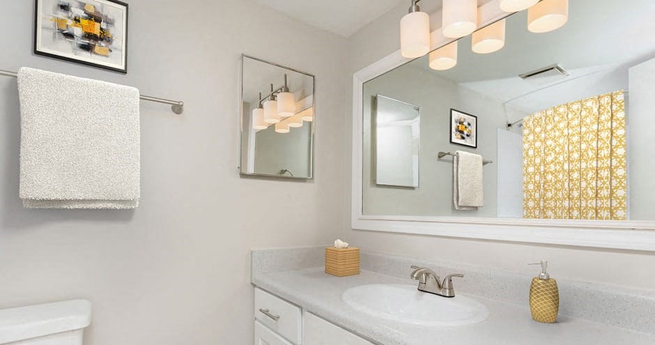 bathroom in apartment that has a large vanity, white cabinets and modern lighting