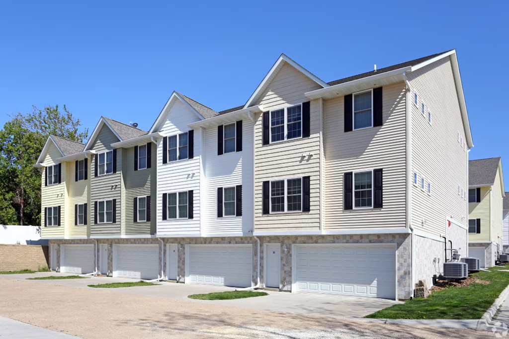 a row of houses with white siding and white garage doors