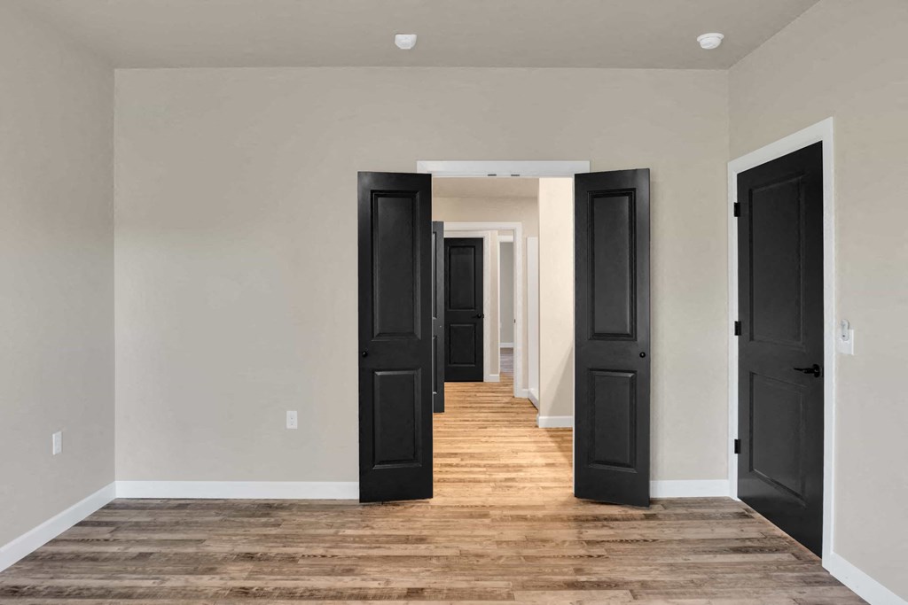 a long hallway with black doors and wood floors
