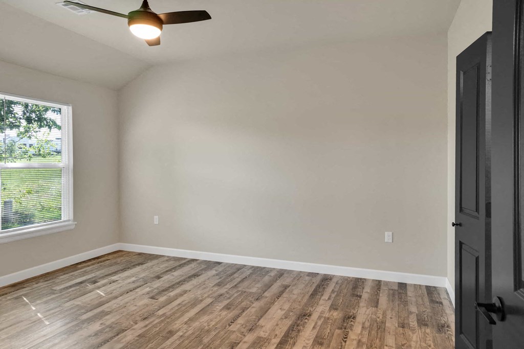 an empty living room with wood floors and a window
