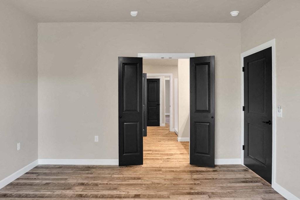 a long hallway with black doors and wood floors