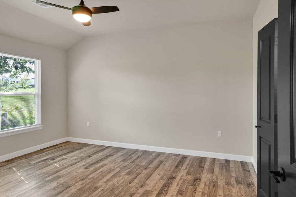 an empty living room with wood floors and a window
