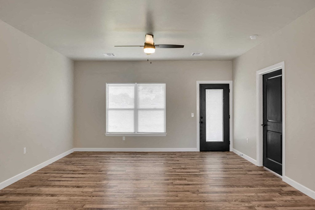 an empty living room with wood floors and a ceiling fan