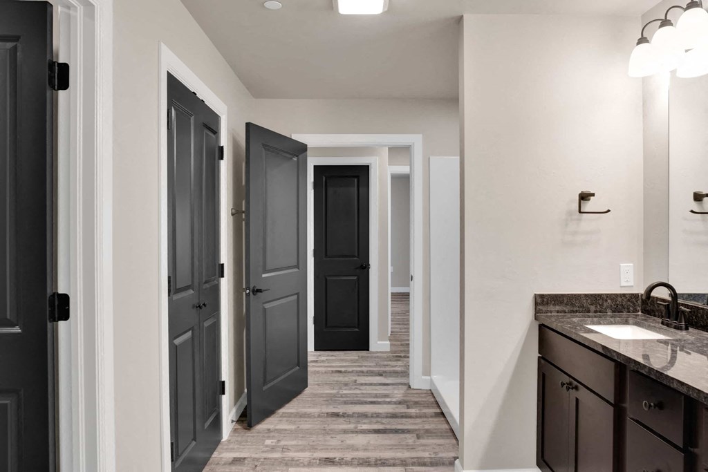 a bathroom with dark doors and a sink and a hallway with closets
