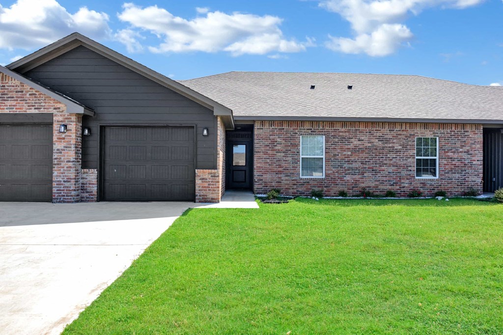 a brick house with black garage doors and a lawn
