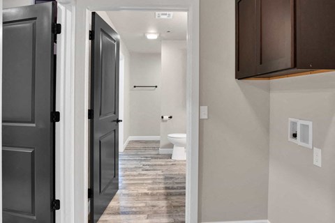 a renovated bathroom with a toilet and a hallway with dark doors