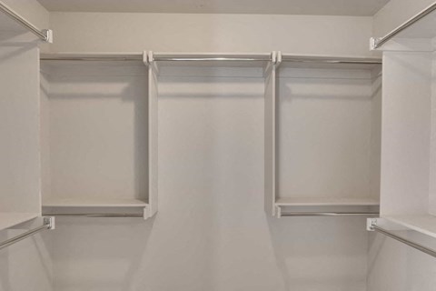 a walk in closet with white walls and white shelves