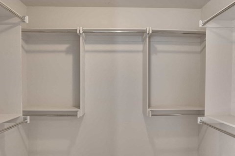 a walk in closet with white walls and white shelves