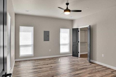 an empty living room with a ceiling fan and a door to a closet