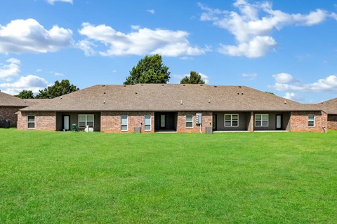 the front of a brick house on a green field