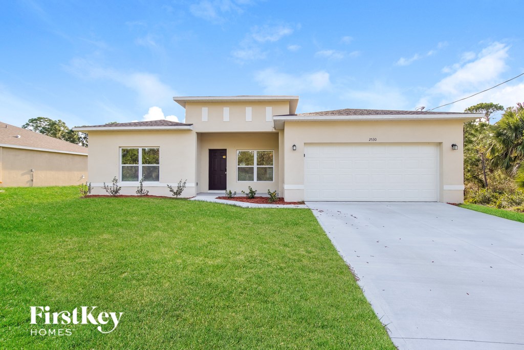 a beige house with a garage and a lawn