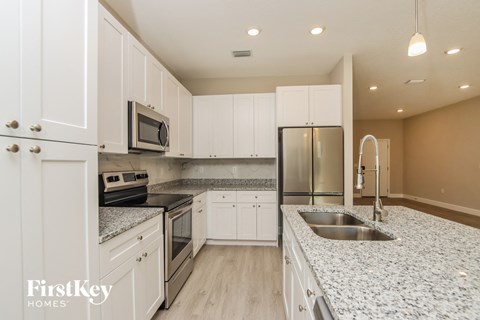 a white kitchen with granite counter tops and stainless steel appliances