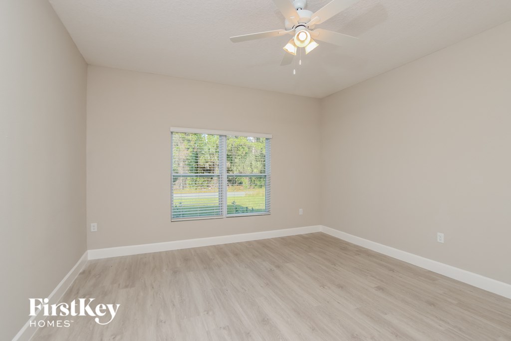 a spacious living room with a window and a ceiling fan