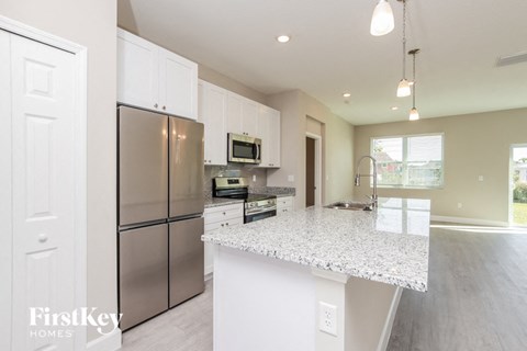 a kitchen with a marble counter top and stainless steel refrigerator