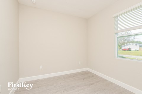 a bedroom with a large window and a wooden floor