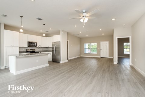 an open kitchen and living room with white cabinets and stainless steel appliances