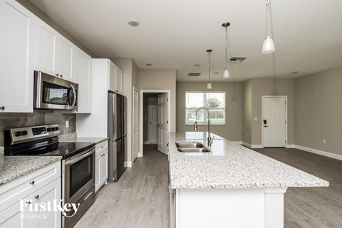 a kitchen with white cabinets and a marble counter top
