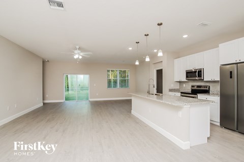 an open kitchen and living room with white cabinets and stainless steel appliances