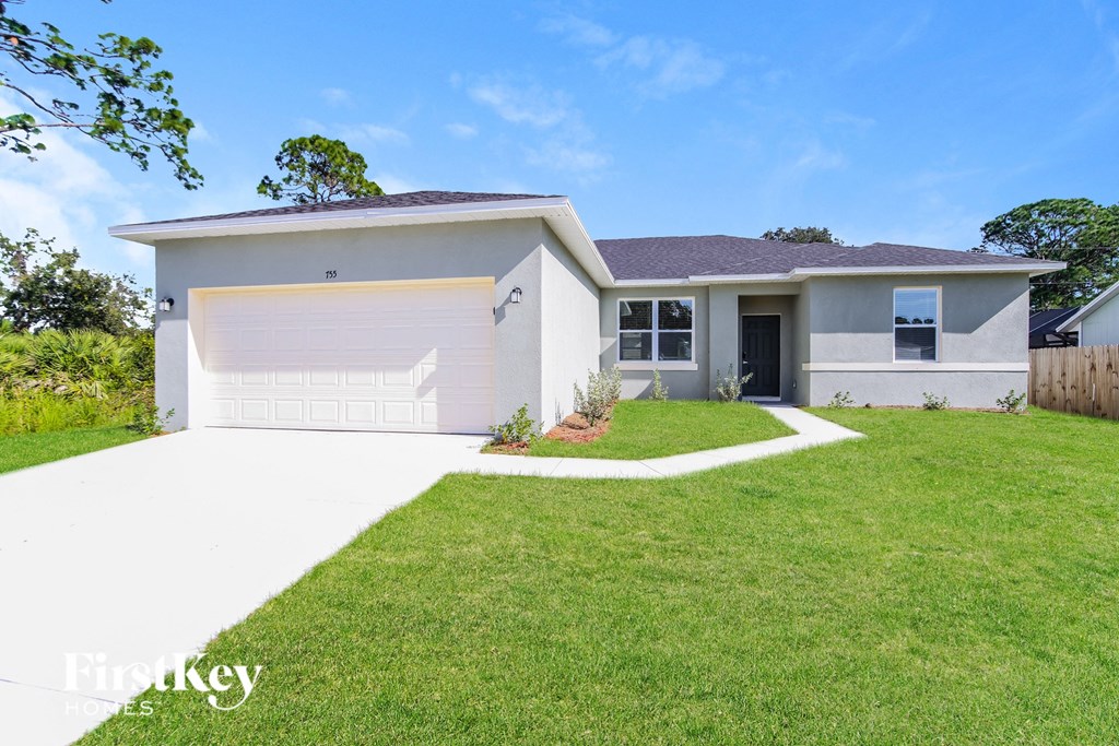 a white house with a lawn and a garage door