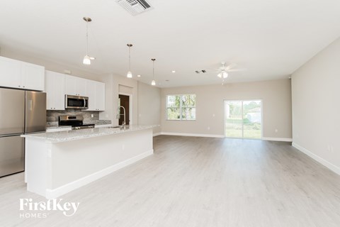 an open kitchen and living room with white cabinets and a white counter top