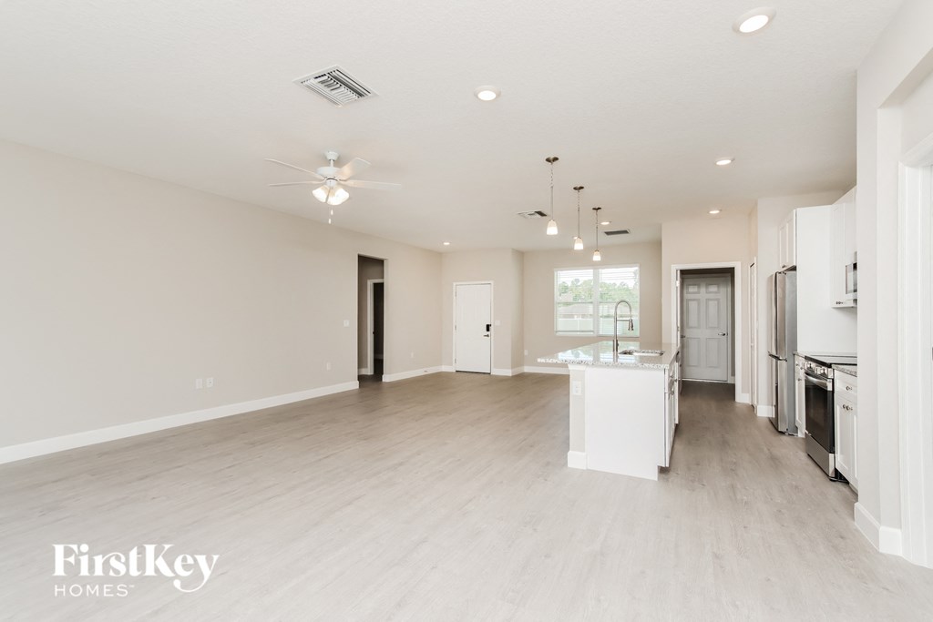 an open kitchen and living room with white walls and wood flooring