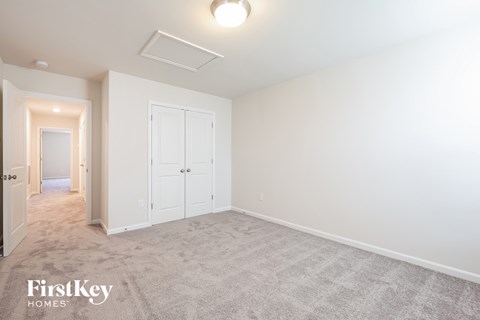 a bedroom with white walls and carpet and a door to a hallway