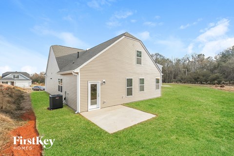 the view of the back of the house from the backyard with the yard and grass